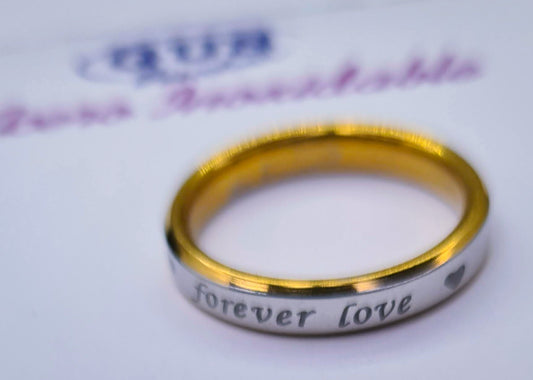 Anillo "Forever Love" tipo alianza de matrimonio o pareja en acero inoxidable bicolor y ancho de 4mm. Se incluye grabado de nombres y fecha importante gratis. Posa sobre un cartón de Gus Barcelona.