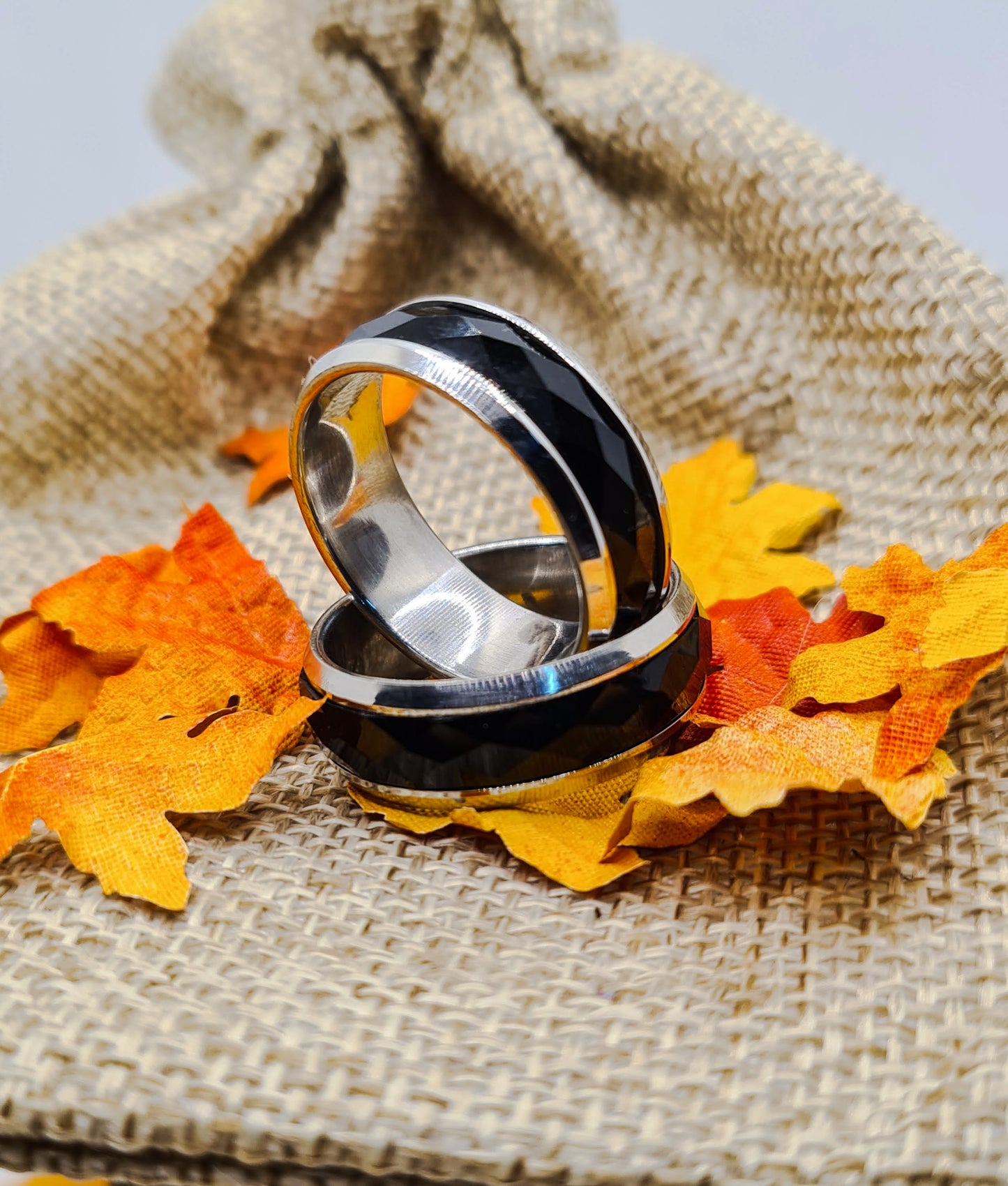 Dos Anillos tipo alianza de matrimonio o pareja en acero inoxidable bicolor negro y ancho de 8mm. Se incluye grabado de nombres y fecha importante gratis. Posan sobre saco.