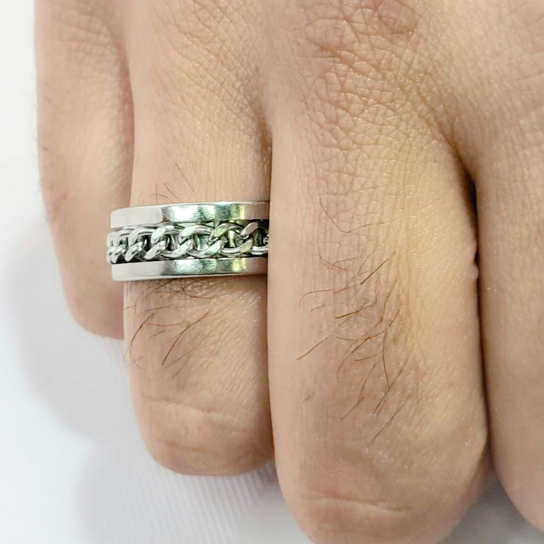 Anillo tipo alianza de matrimonio o pareja en acero inoxidable con cadena y ancho de 8mm. Se incluye grabado de nombres y fecha importante gratis. Posa sobre mano de hombre.