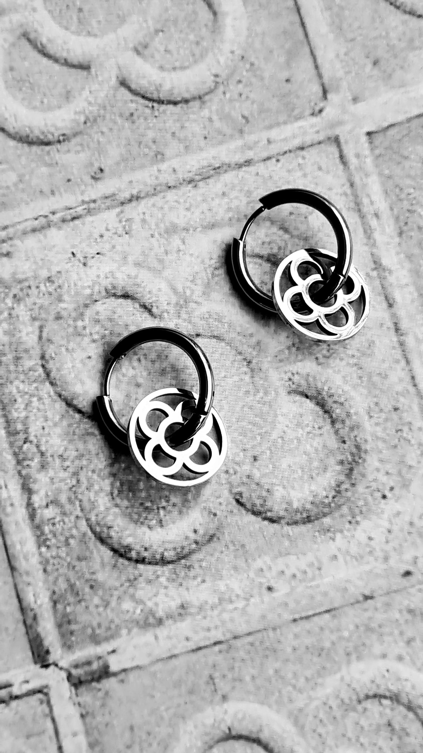 Aros con la Flor de Barcelona de acero inoxidable circular para mujer. Sobre baldosa Flor de Barcelona.
