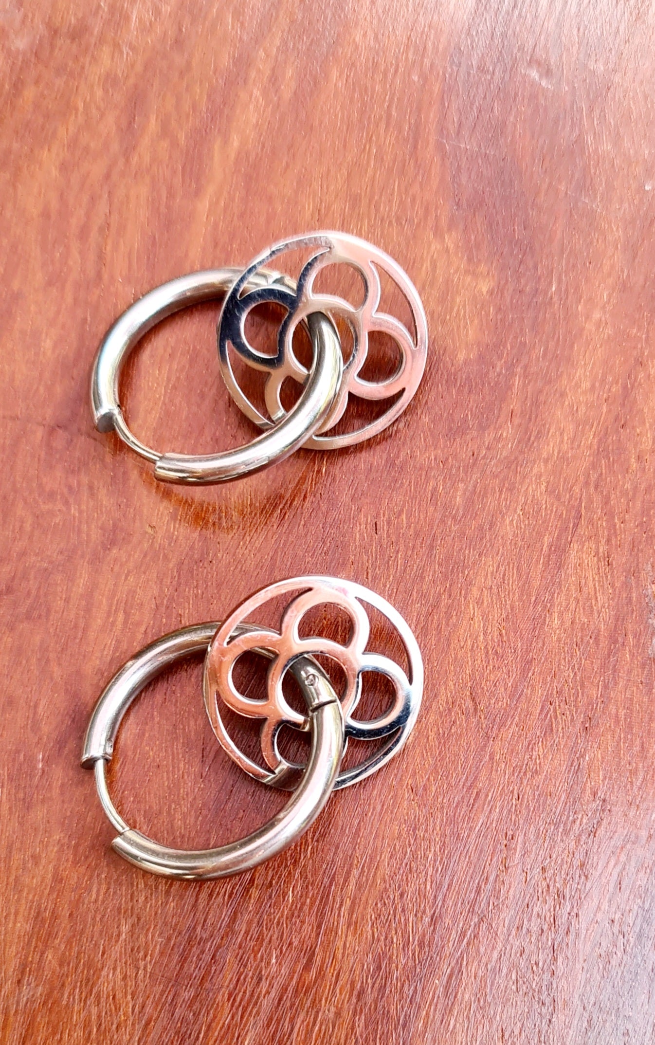 Aros con la Flor de Barcelona de acero inoxidable circular para mujer. Fondo de Madera.