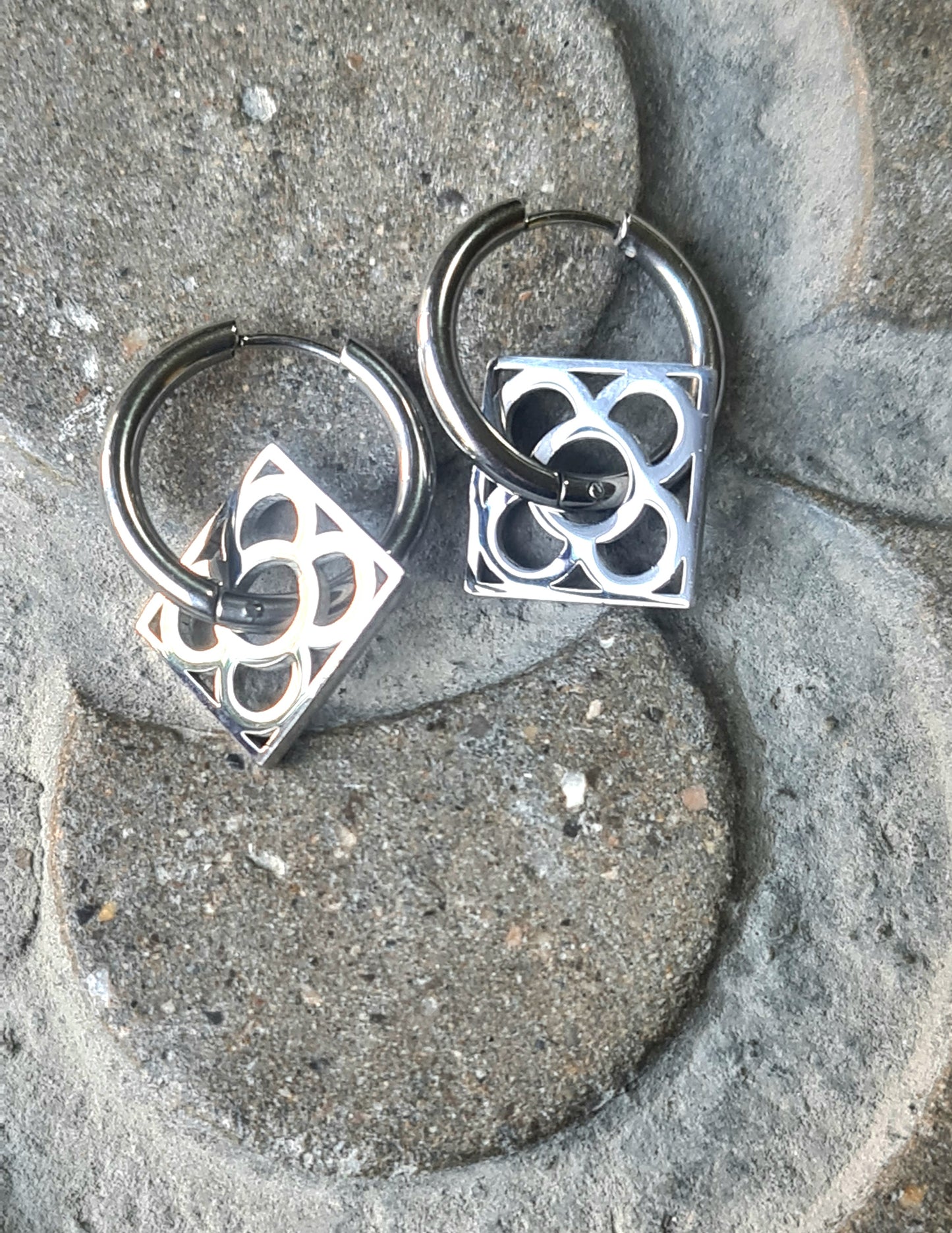 Aros con la Flor de Barcelona de acero inoxidable cuadrada para mujer. Sobre baldosa Flor de Barcelona.