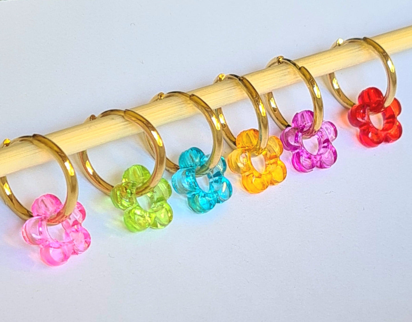 Aros acero inoxidable dorados con Flor de Acrílico para mujer. Fondo blanco.