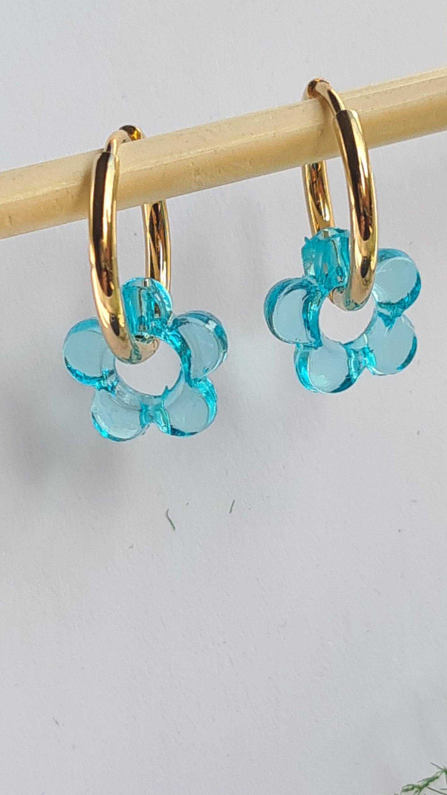 Aros acero inoxidable dorados con Flor de Acrílico para mujer. Fondo blanco.
