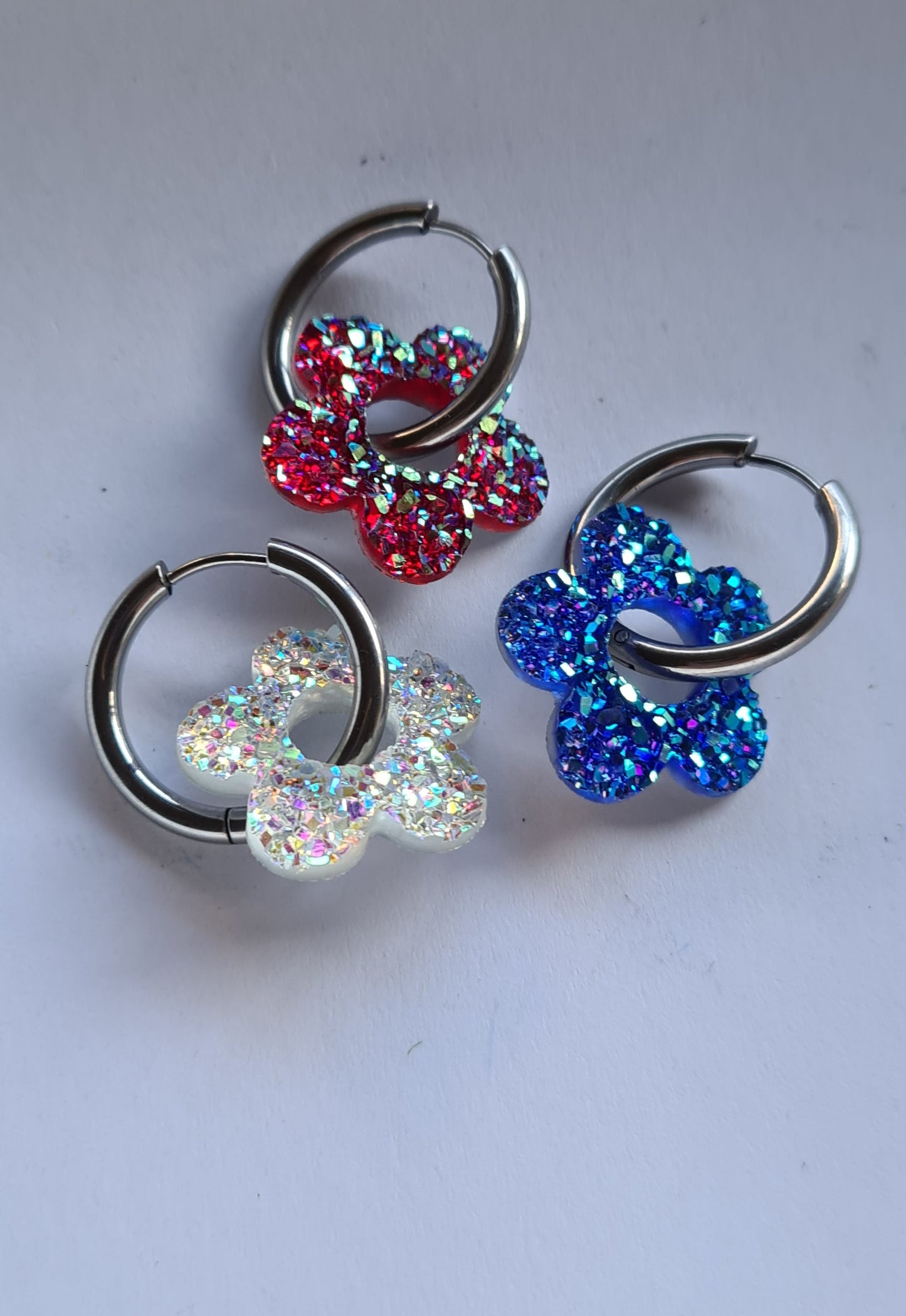Aros acero inoxidable plateados con Flor de Acrílico Brillante para mujer. Fondo blanco.