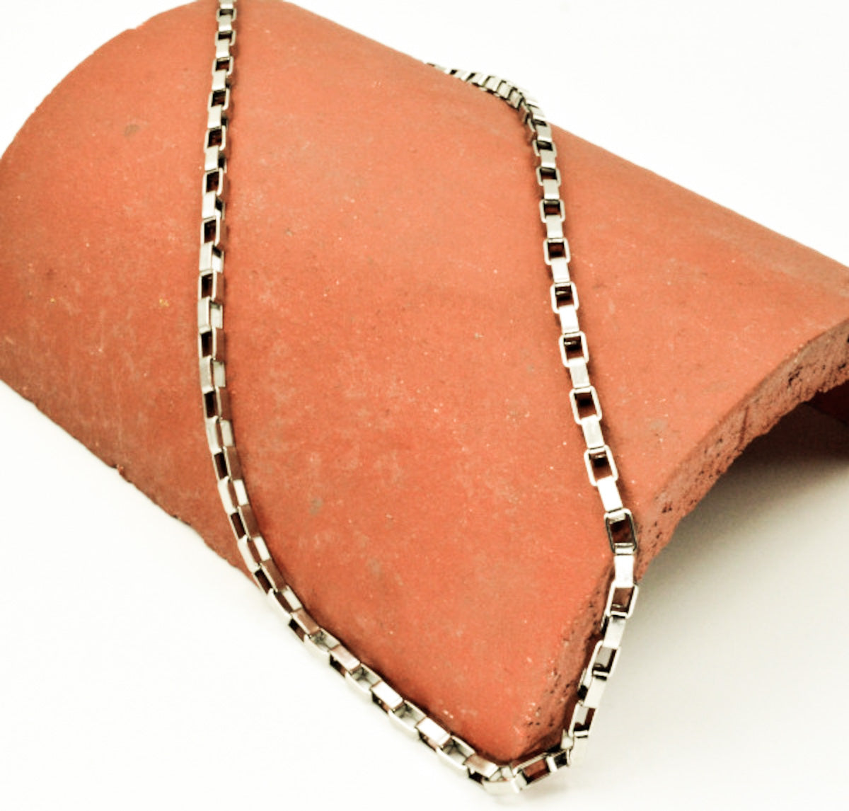 Cadena acero inoxidable modelo Veneciano, 3 anchos. Posa sobre un ladrillo.