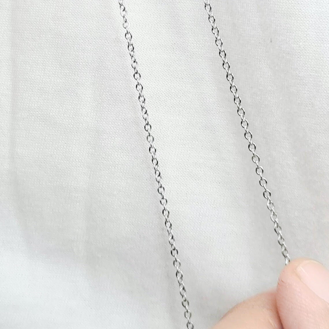 Cadena acero inoxidable modelo Eslabón Forzado Fino, 3 anchos. Posa sobre mano de modelo.