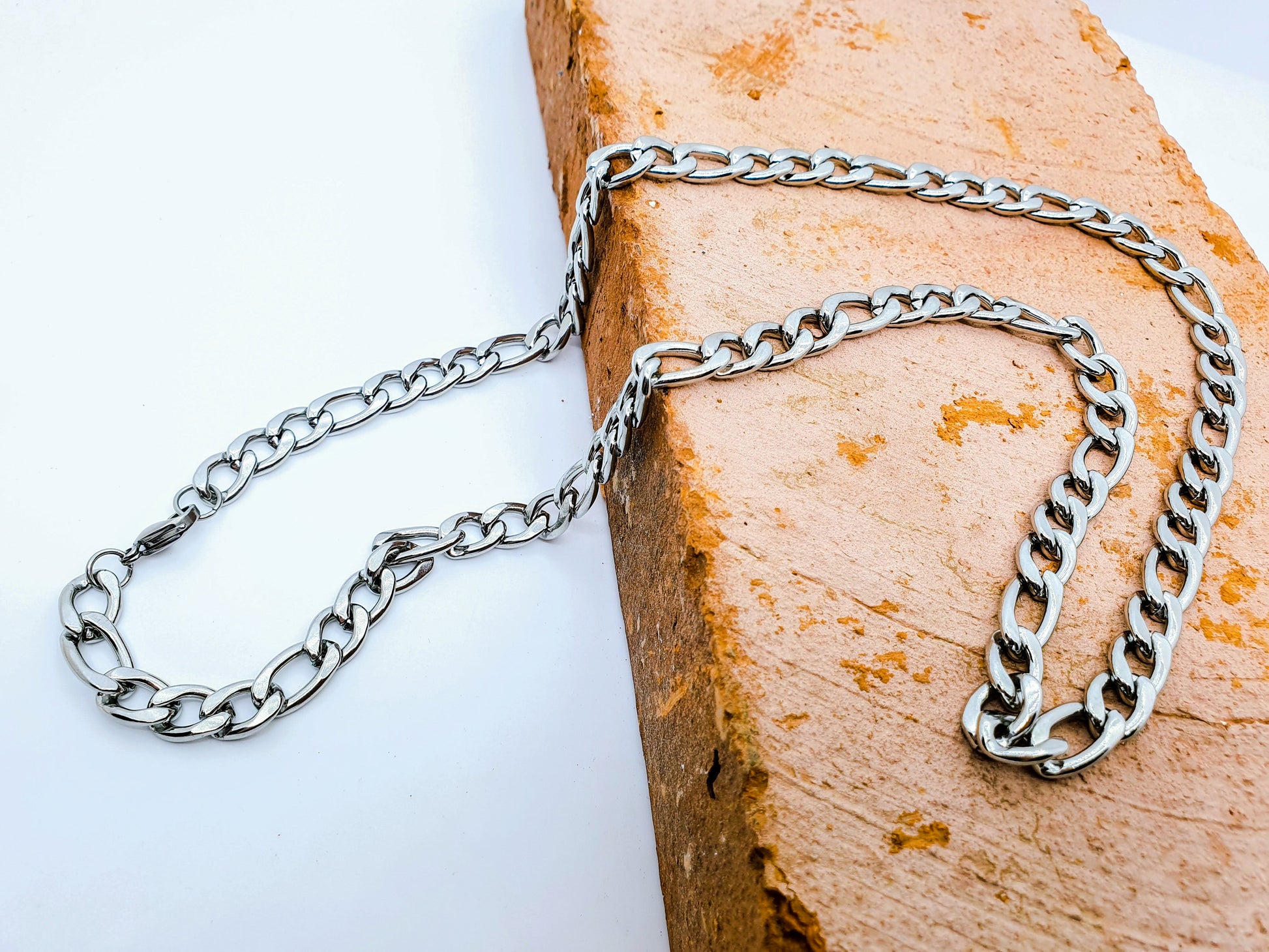 Cadena acero inoxidable modelo Fígaro, 4 anchos. Posa sobre un ladrillo.