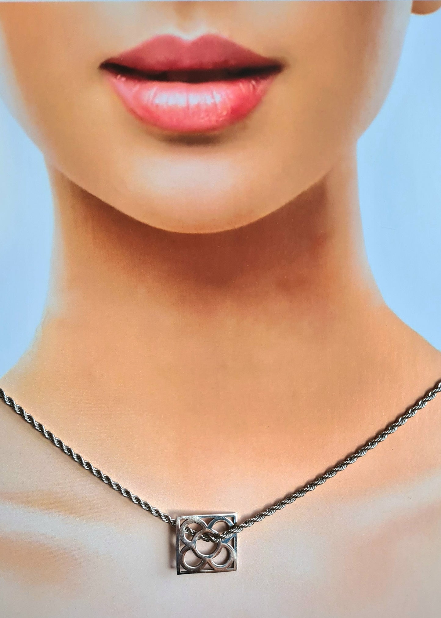 Colgante con la Flor de Barcelona de acero inoxidable cuadrada para mujer. Sobre busto mujer.