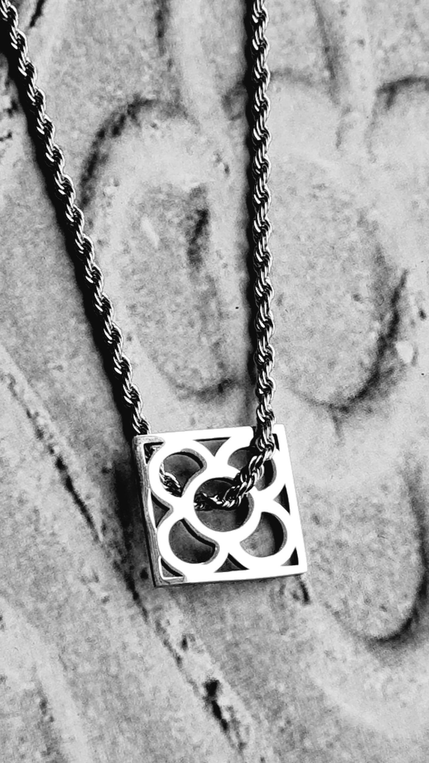 Colgante con la Flor de Barcelona de acero inoxidable cuadrada para mujer. Sobre baldosa Flor de Barcelona.
