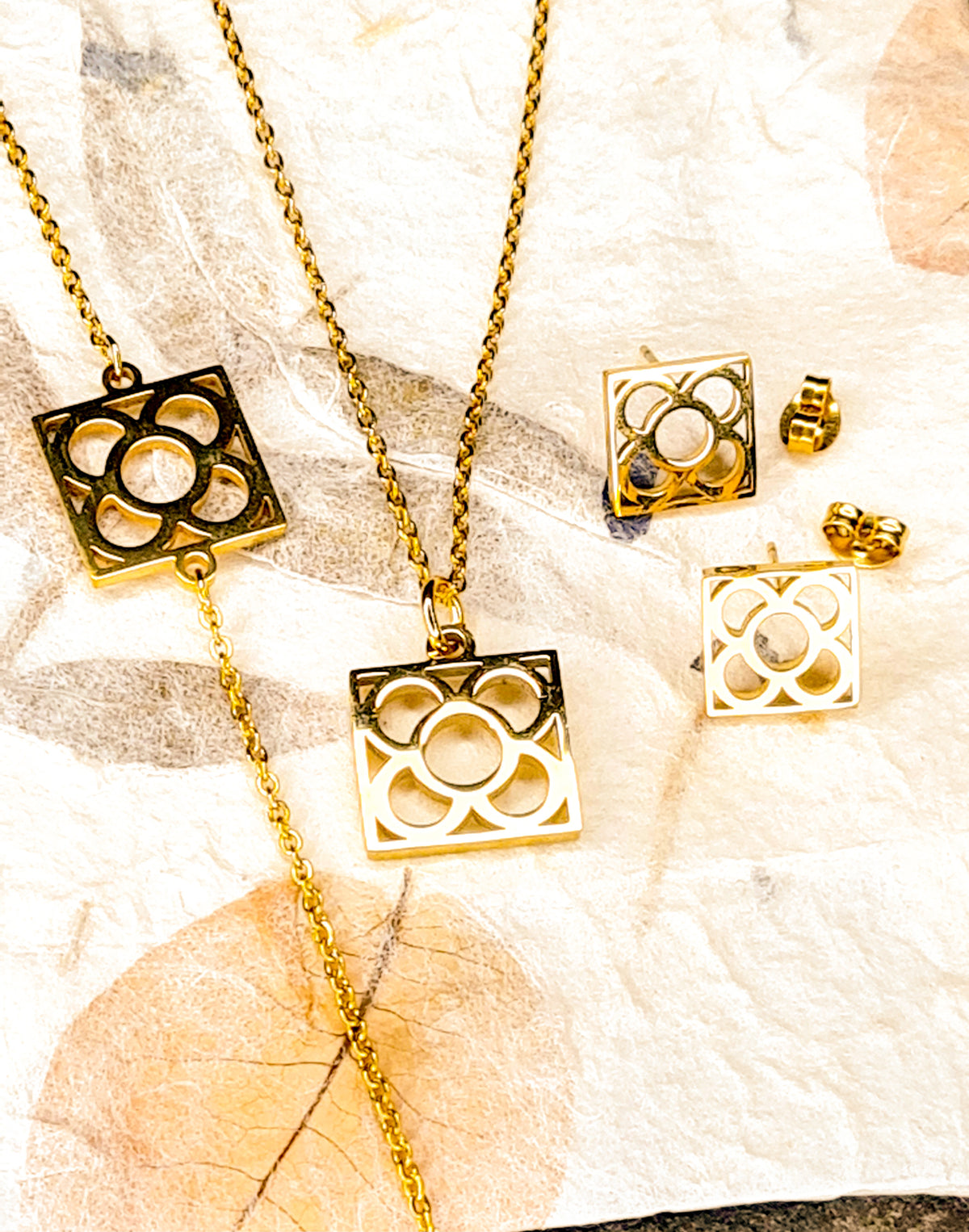 Conjunto Flor de Barcelona Acero Inoxidable dorado para mujer. Posa sobre bolsa de papel.