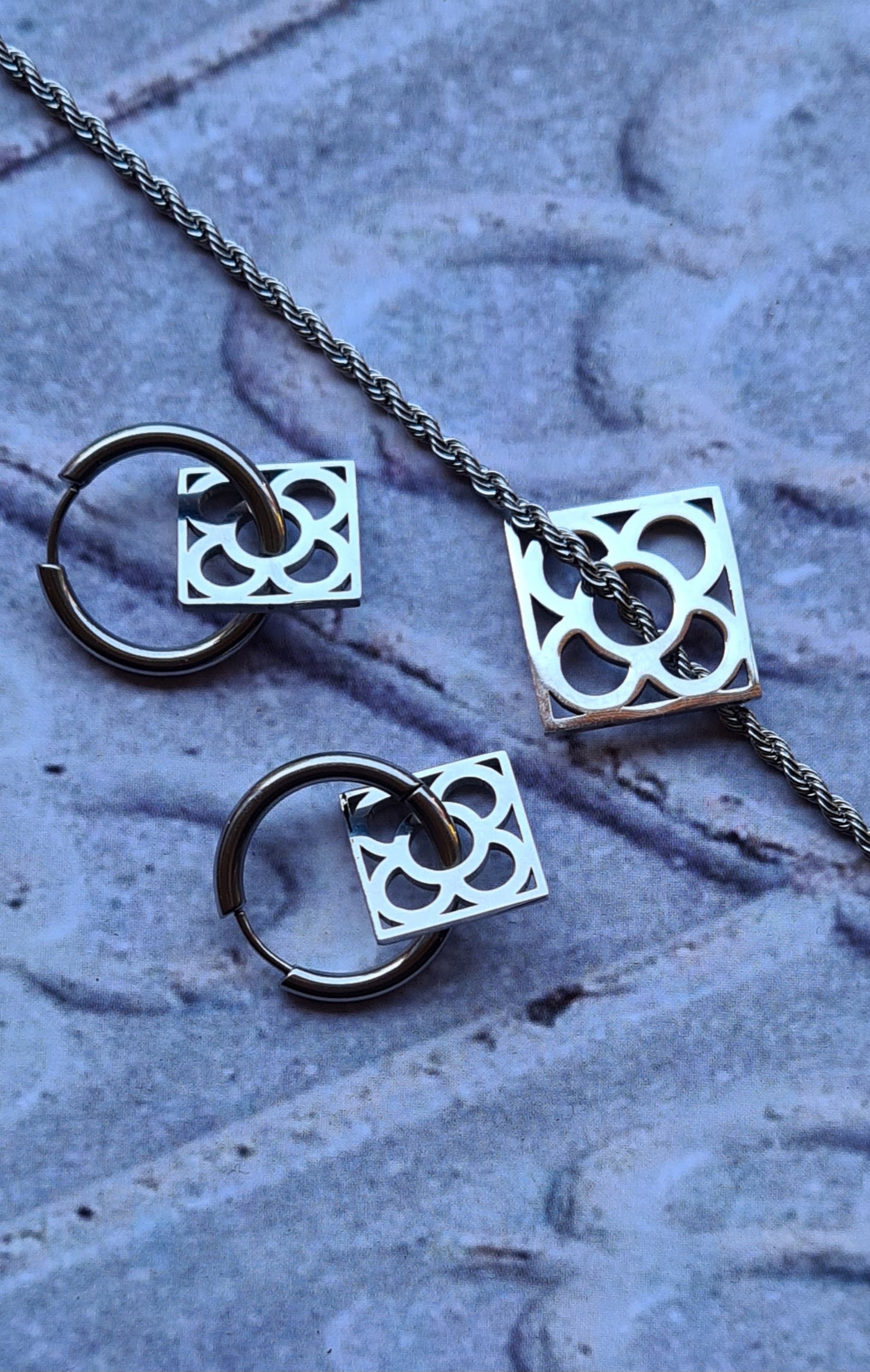 Conjunto con la Flor de Barcelona de acero inoxidable cuadrada para mujer. Sobre baldosa Flor de Barcelona.