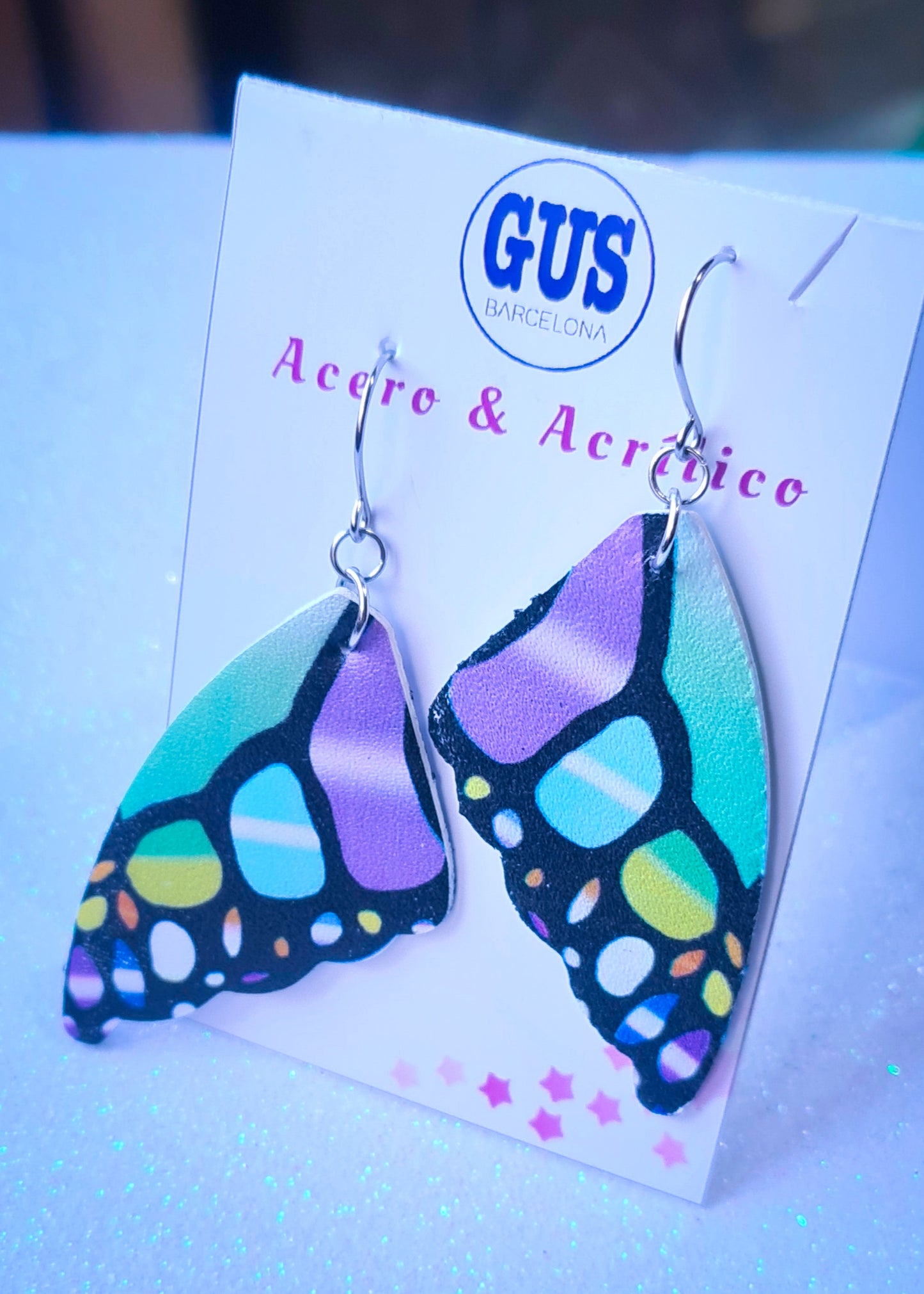 Pendientes Alas de Mariposa para mujer en Acero y Acrílico. Posa sobre cartón blanco.