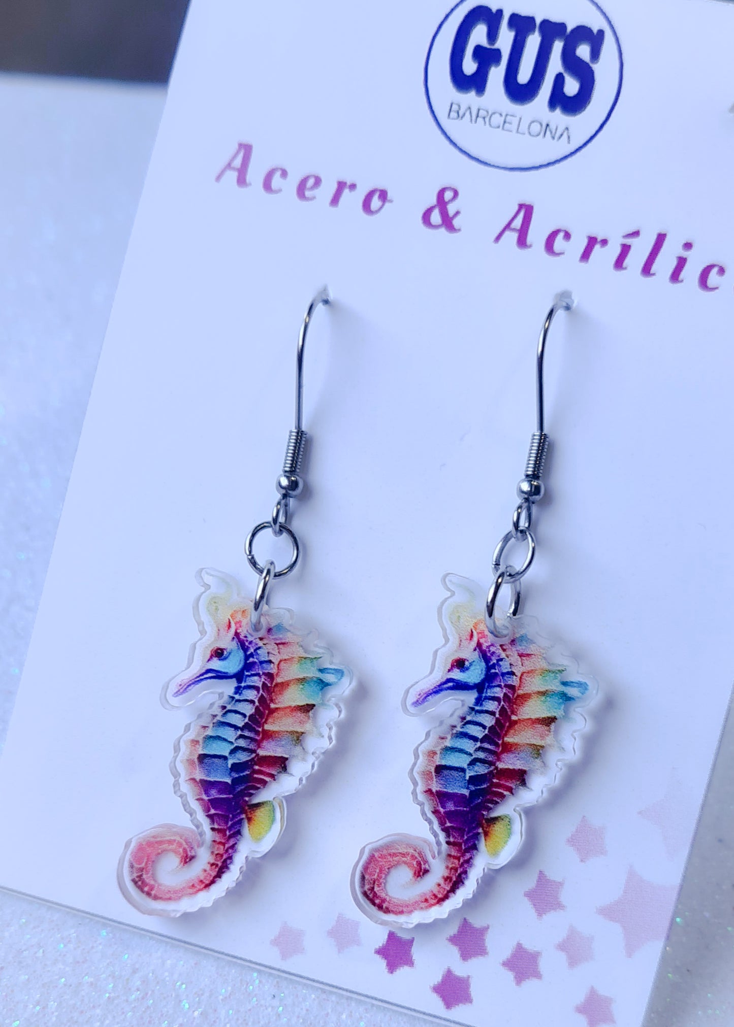 Pendientes Caballito de mar para mujer en Acero y Acrílico. Posa sobre cartón blanco.