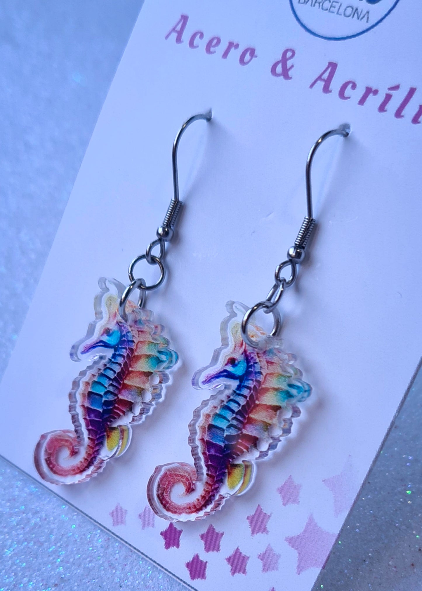 Pendientes Caballito de mar para mujer en Acero y Acrílico. Posa sobre cartón blanco.