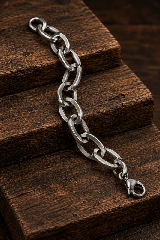 Pulsera de acero inoxidable con eslabones ovalados presentada sobre madera.