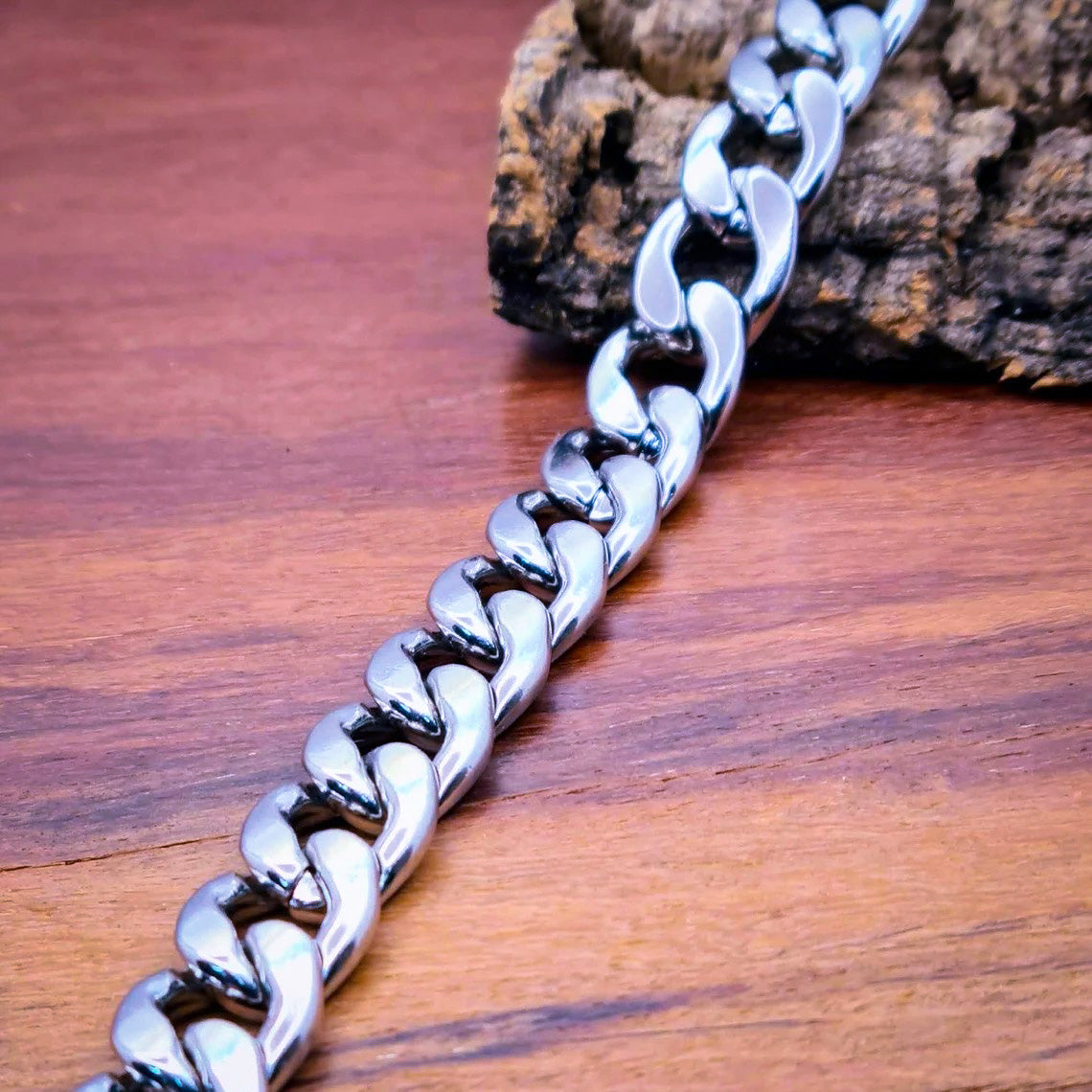 Pulsera acero inoxidable modelo Eslabón Grande, 12mm de ancho. Posa sobre madera.