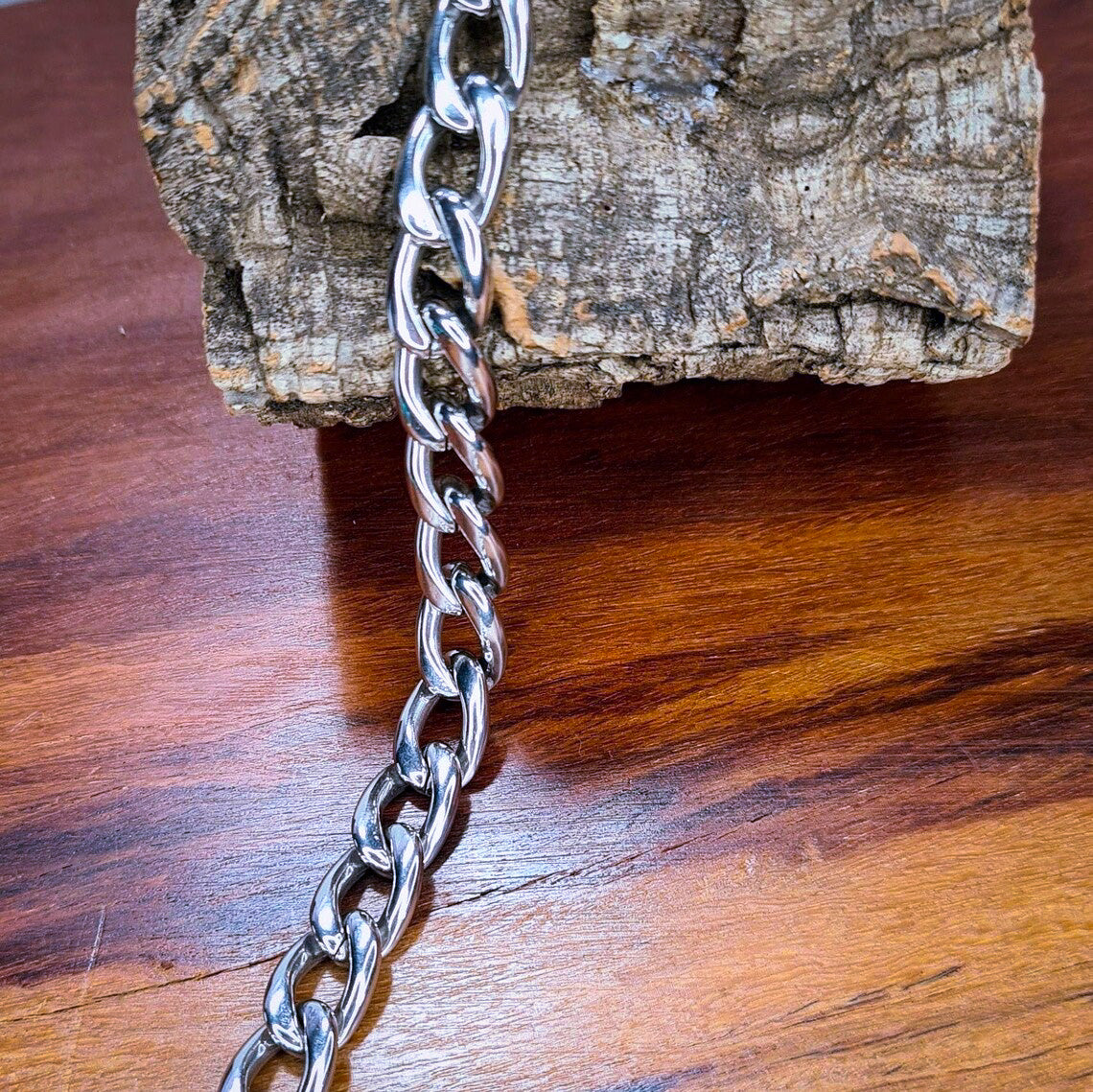 Pulsera acero inoxidable modelo Eslabón Largo, 10mm de ancho. Posa sobre madera.