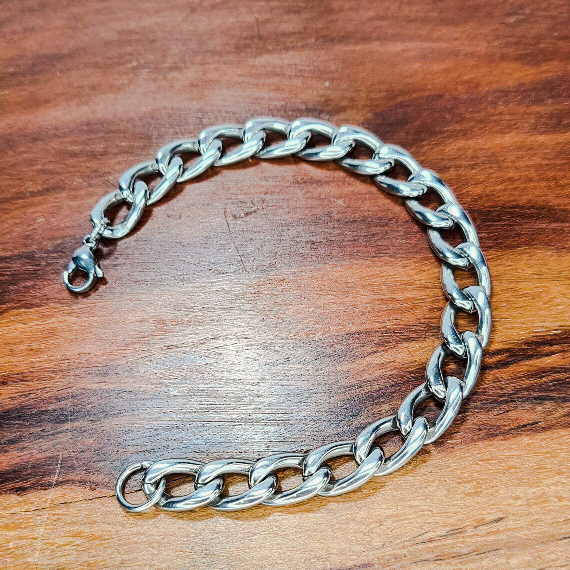 Pulsera acero inoxidable modelo Eslabón Largo, 10mm de ancho. Posa sobre madera.