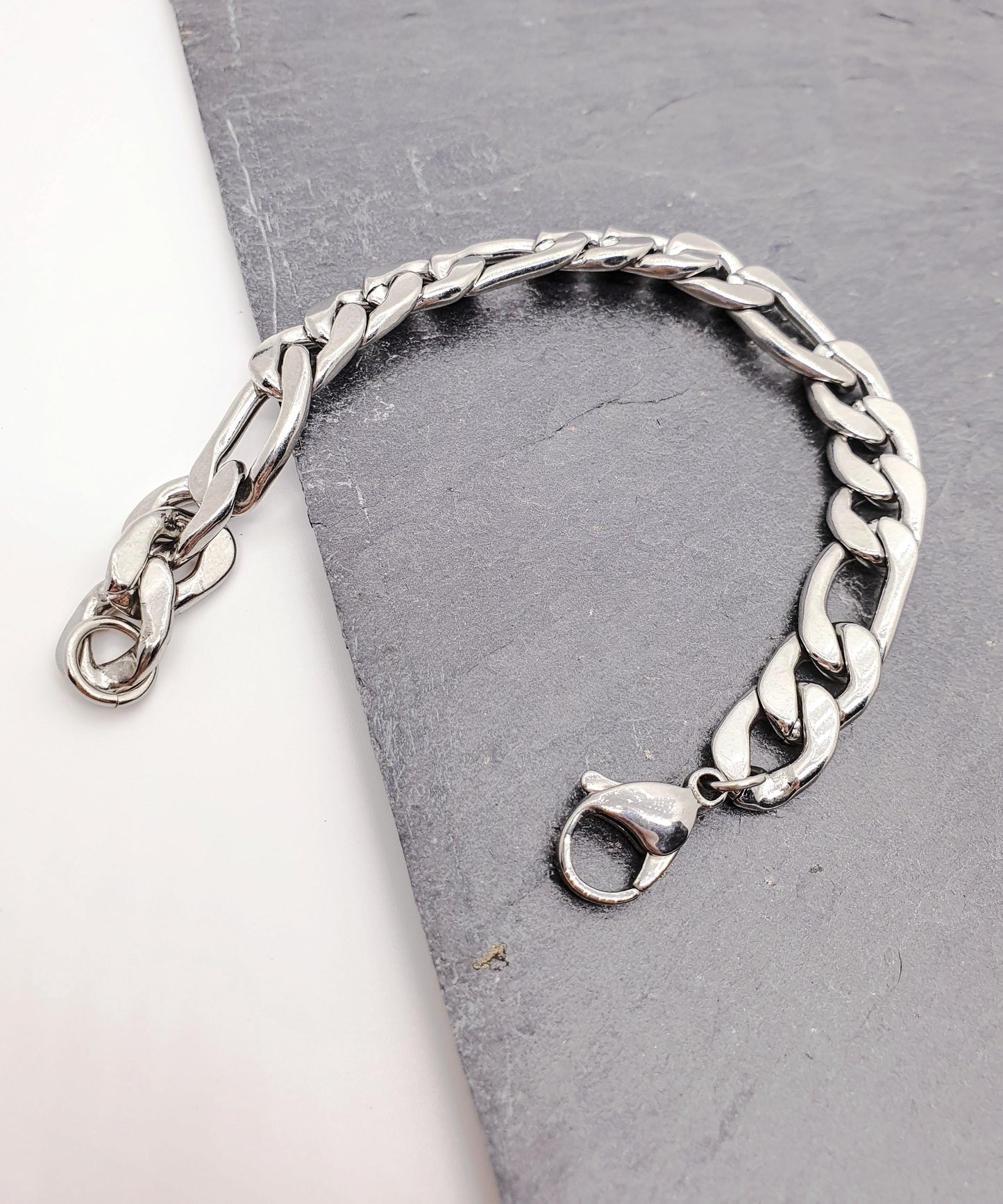 Pulsera acero inoxidable modelo Fígaro, 5 anchos. Posa sobre fondo blanco y pizarra.