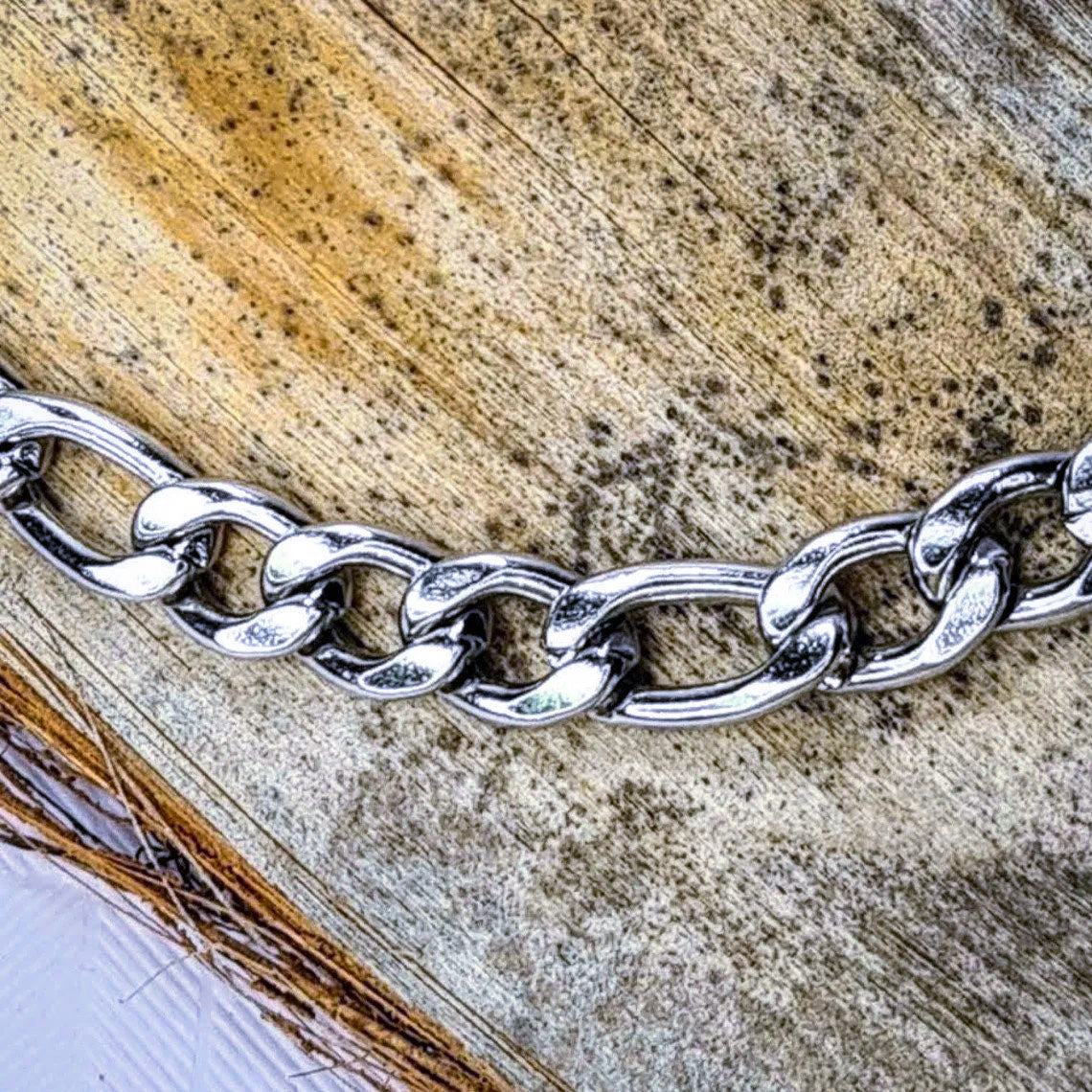 Pulsera acero inoxidable modelo Fígaro, 5 anchos. Posa sobre madera.