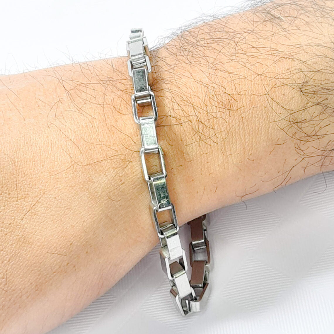 Pulsera acero inoxidable modelo de cajón, 6mm de ancho. Posa sobre mano de modelo.