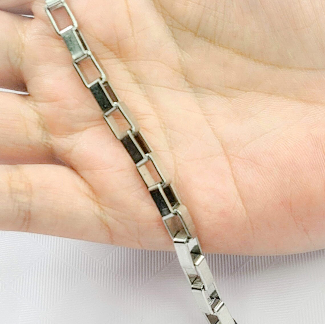Pulsera acero inoxidable modelo de cajón, 6mm de ancho. Posa sobre mano de modelo.