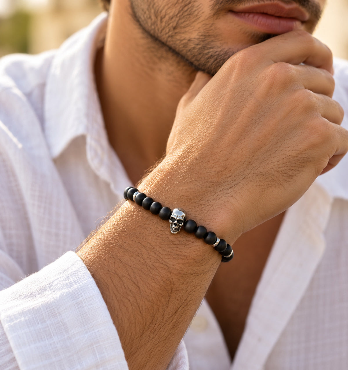 Hombre llevando pulsera negra de ónix mate de 5 mm con calavera central de acero.