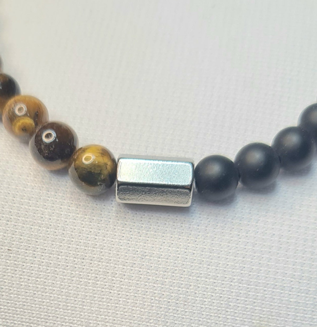 Detalle de pulsera de ojo de tigre y ónix negro mate.