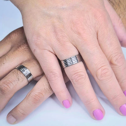 Dos Anillos tipo alianza de matrimonio o pareja en acero inoxidable bicolor y ancho de 6mm. Se incluye grabado de nombres y fecha importante gratis. Posan sobre mano de pareja.