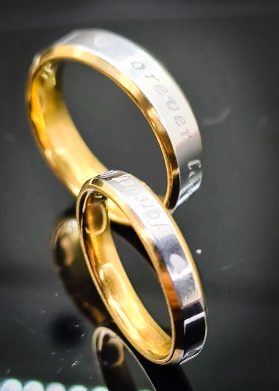 Anillos "Forever Love" tipo alianza de matrimonio o pareja en acero inoxidable bicolor y ancho de 4mm y 6mm. Se incluye grabado de nombres y fecha importante gratis. Posan sobre fondo negro brillante.