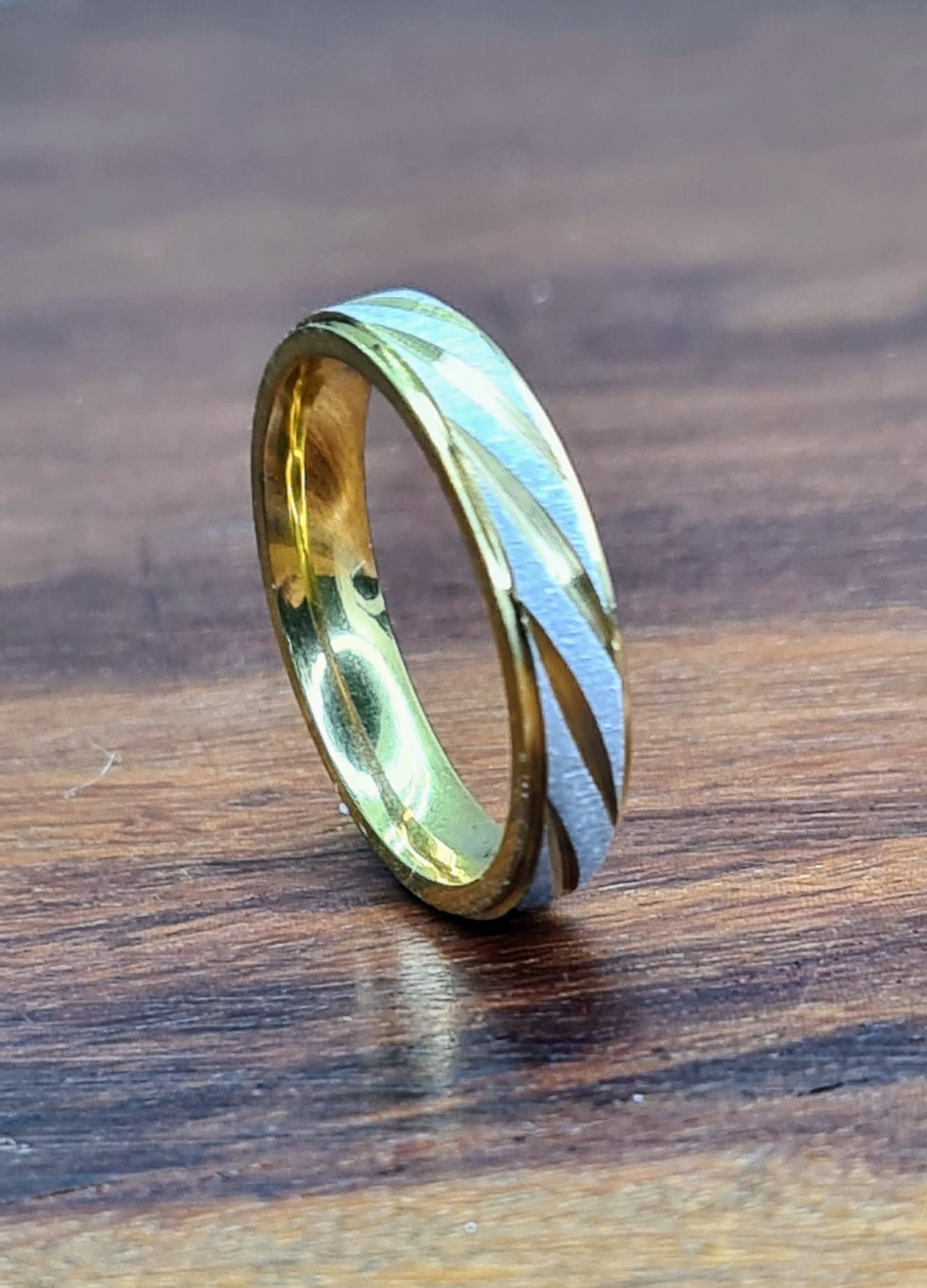 Anillo de acero inoxidable bicolor sobre superficie de madera.