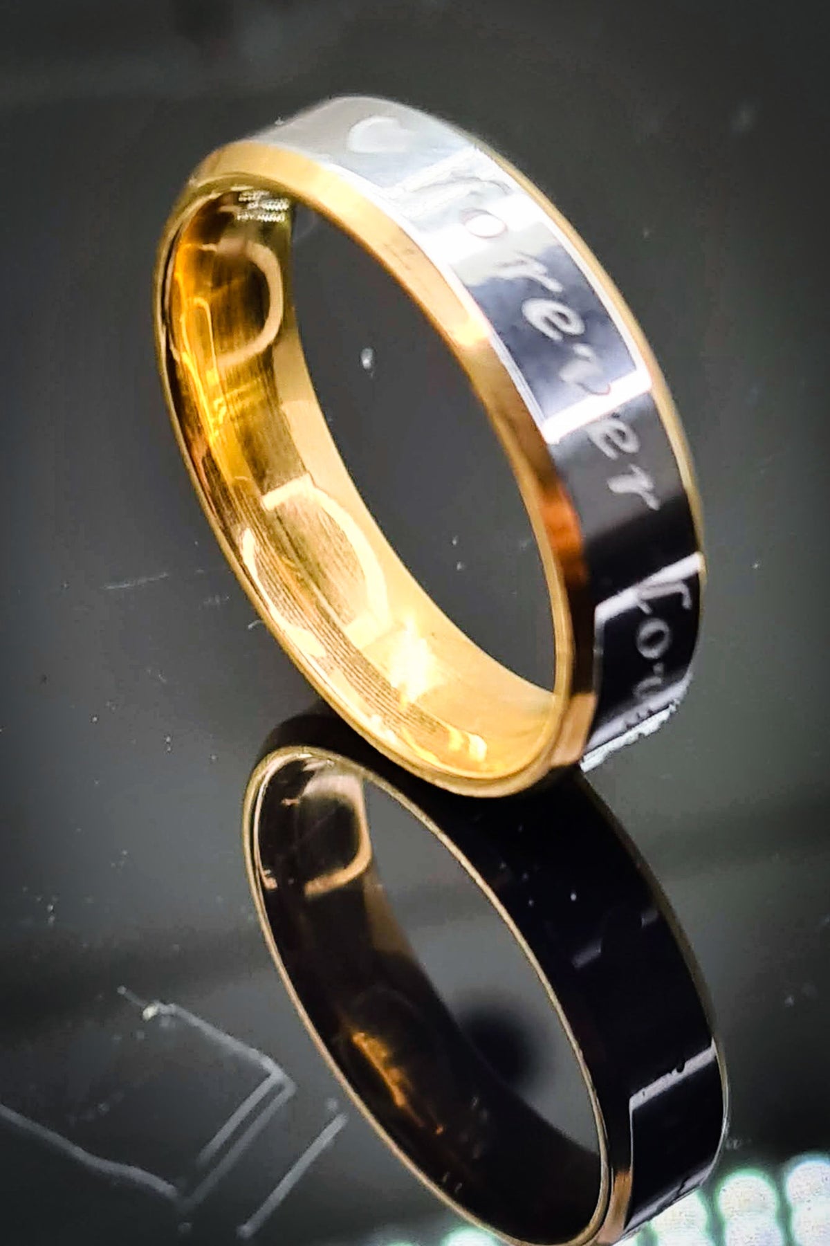 Anillo de acero inoxidable bicolor de 6 mm sobre superficie negra con reflejo.