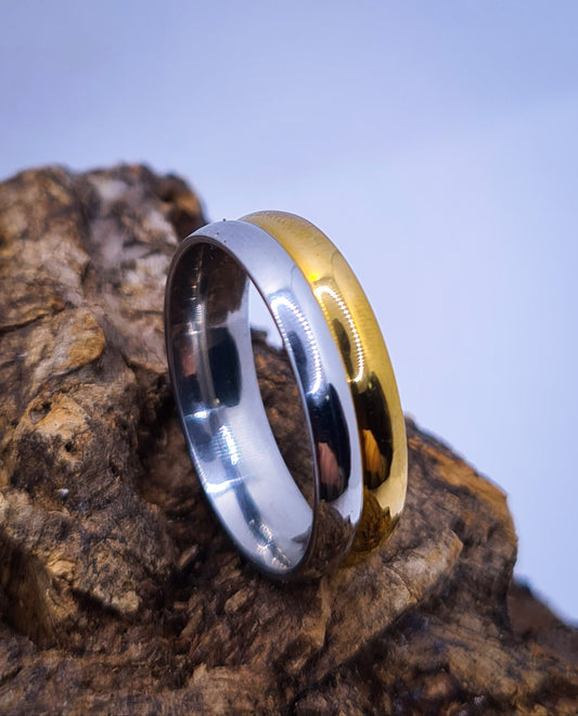 Anillo tipo alianza de matrimonio o pareja en acero inoxidable bicolor y ancho de 6mm. Se incluye grabado de nombres y fecha importante gratis. Posa sobre tronco.