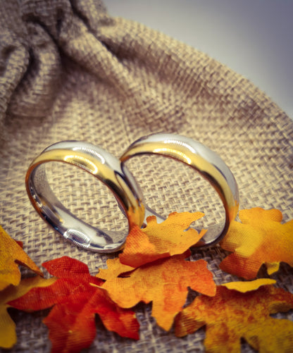 Dos Anillos tipo alianza de matrimonio o pareja en acero inoxidable bicolor y ancho de 6mm. Se incluye grabado de nombres y fecha importante gratis. Posan sobre saco.