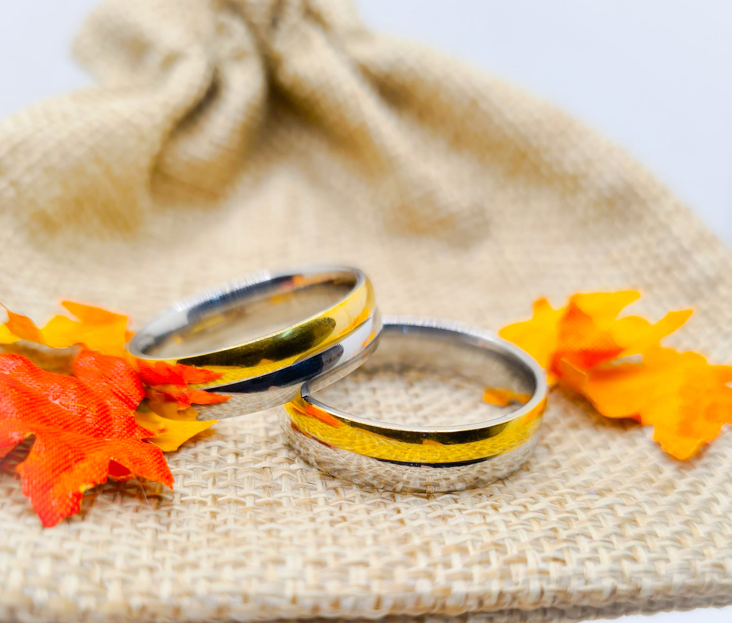 Dos Anillos tipo alianza de matrimonio o pareja en acero inoxidable bicolor y ancho de 6mm. Se incluye grabado de nombres y fecha importante gratis. Posan sobre saco.