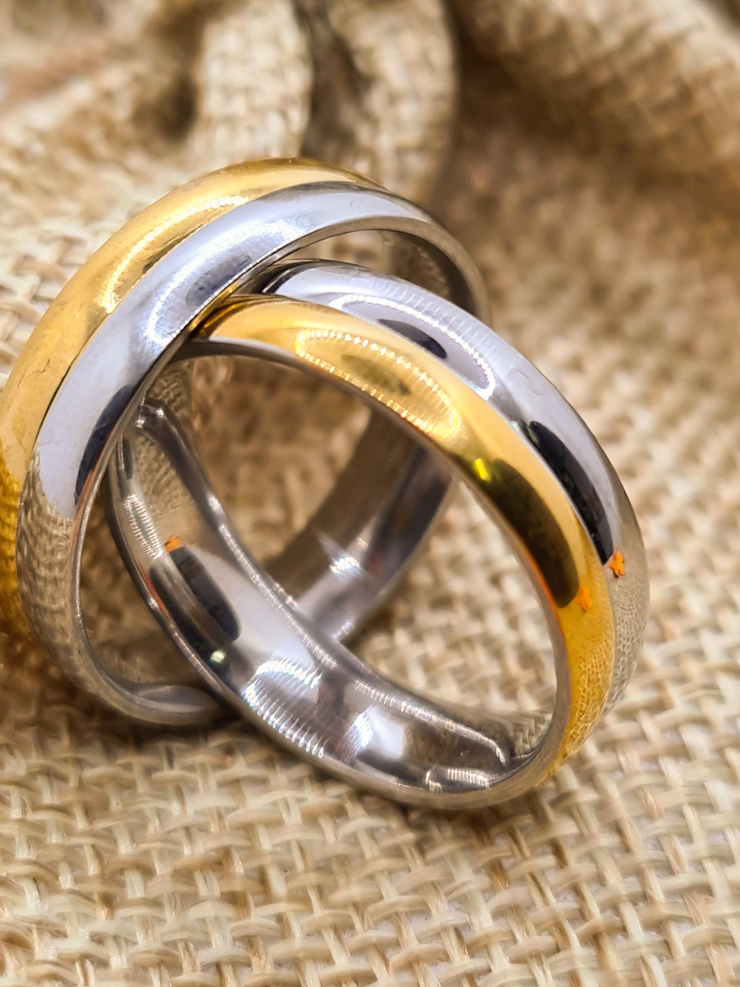 Dos Anillos tipo alianza de matrimonio o pareja en acero inoxidable bicolor y ancho de 6mm. Se incluye grabado de nombres y fecha importante gratis. Posan sobre saco.
