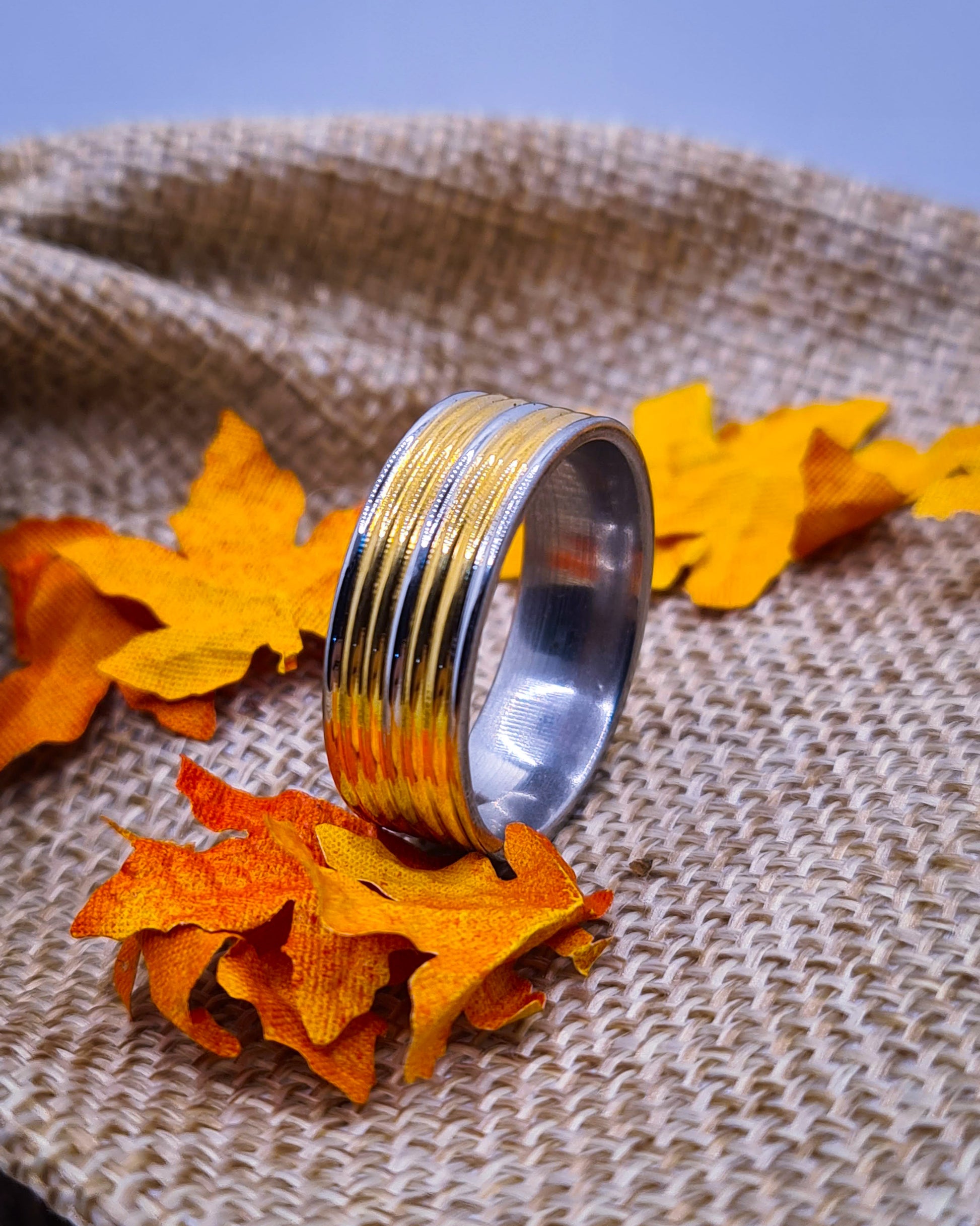 Anillo tipo alianza de matrimonio o pareja en acero inoxidable bicolor y ancho de 8mm. Se incluye grabado de nombres y fecha importante gratis. Posa sobre saco.