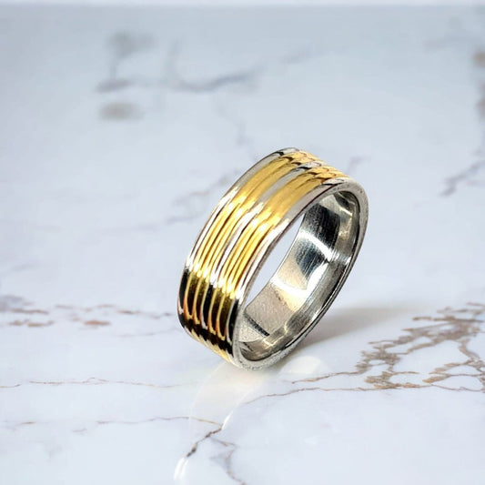 Anillo tipo alianza de matrimonio o pareja en acero inoxidable bicolor y ancho de 8mm. Se incluye grabado de nombres y fecha importante gratis. Posa sobre mármol.