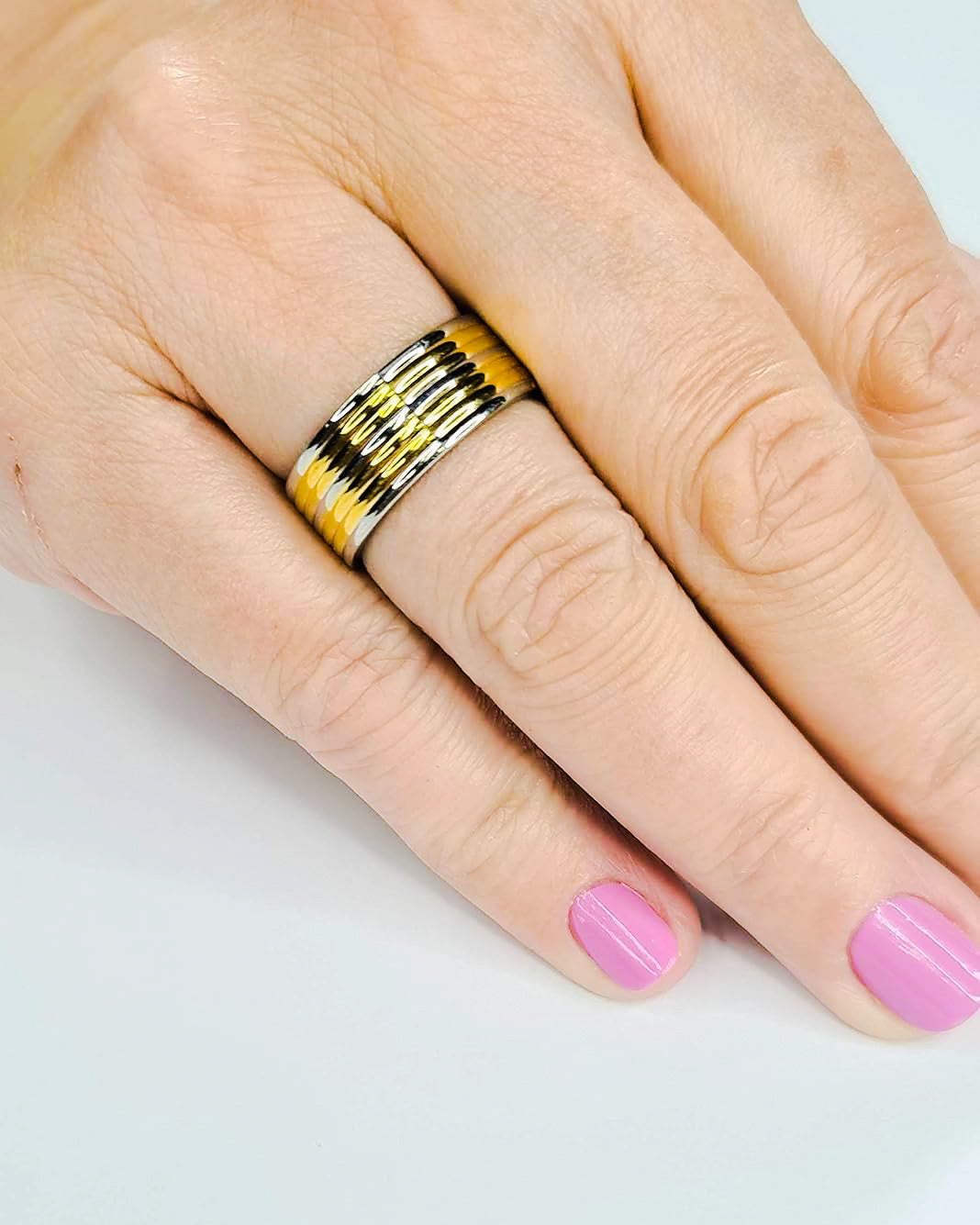 Anillo tipo alianza de matrimonio o pareja en acero inoxidable bicolor y ancho de 8mm. Se incluye grabado de nombres y fecha importante gratis. Posa sobre mano de mujer.