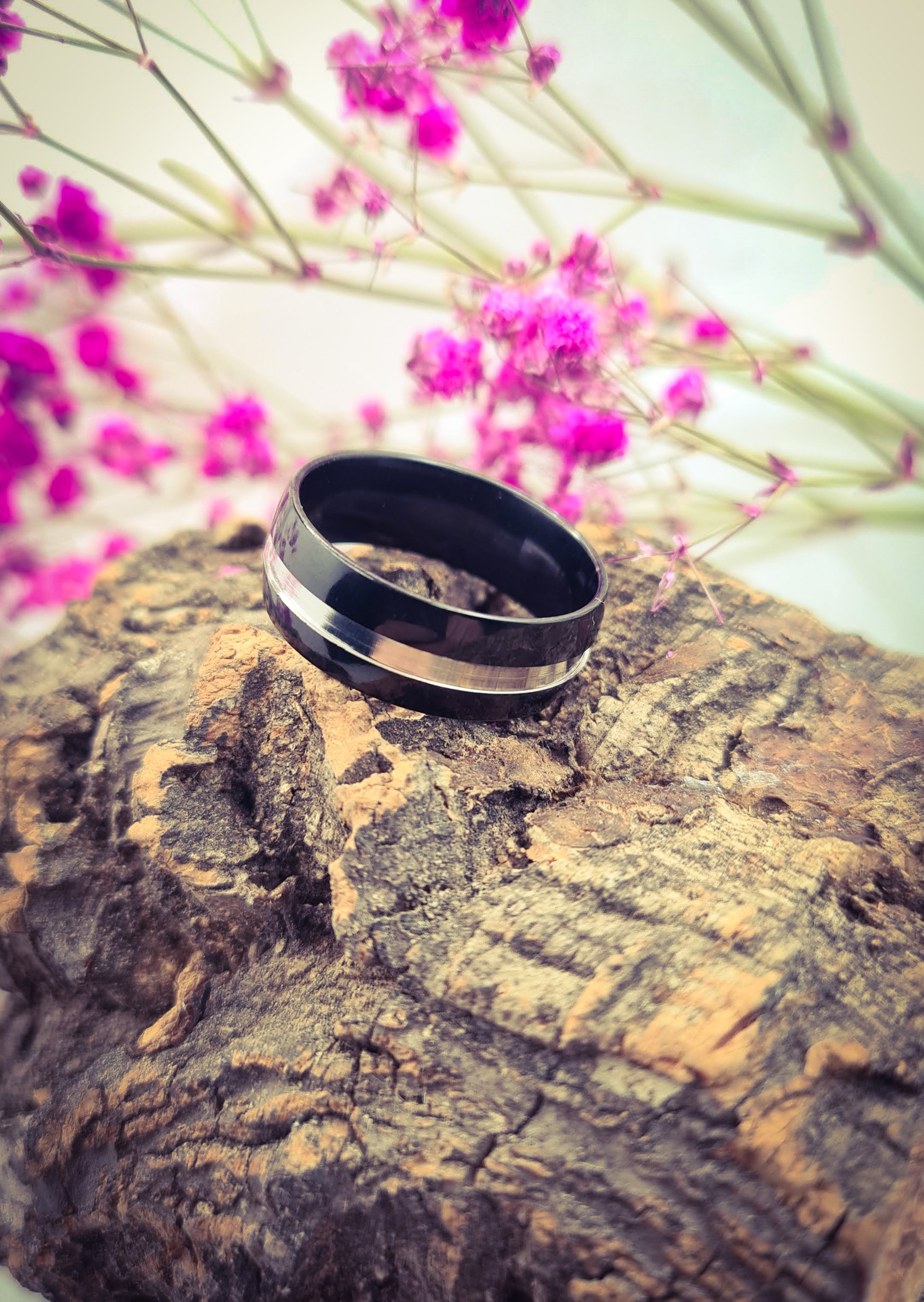 Anillo tipo alianza de matrimonio o pareja en acero inoxidable bicolor negro y ancho de 8mm. Se incluye grabado de nombres y fecha importante gratis. Posa sobre tronco.