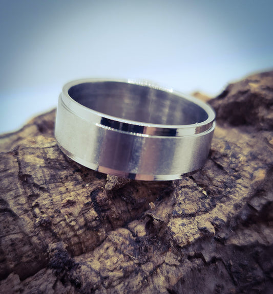 Anillo tipo alianza de matrimonio o pareja en acero inoxidable biselado y ancho de 8mm. Se incluye grabado de nombres y fecha importante gratis. Posa sobre tronco.