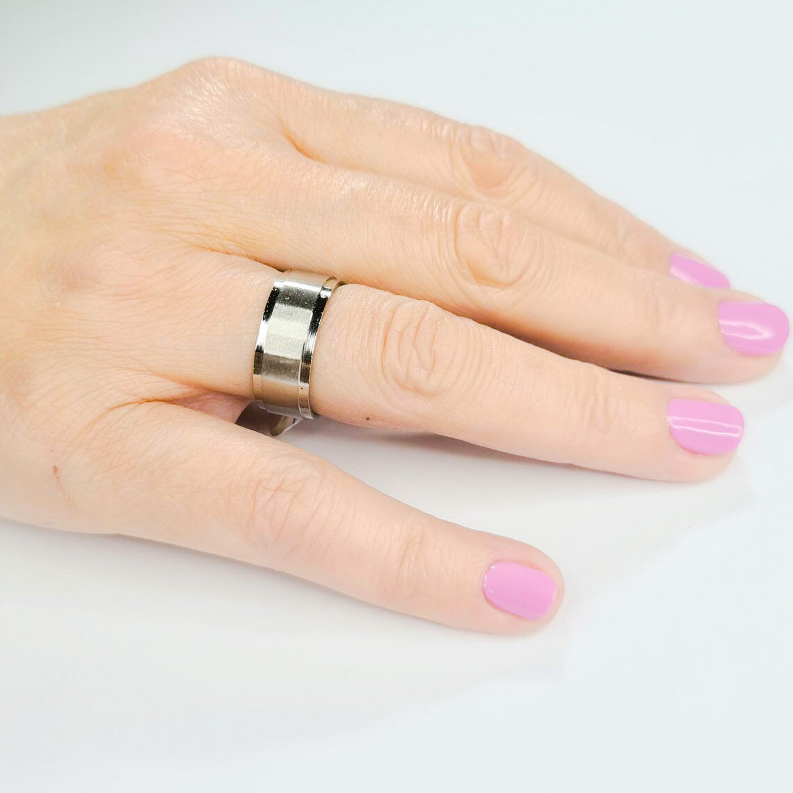 Anillo tipo alianza de matrimonio o pareja en acero inoxidable biselado y ancho de 8mm. Se incluye grabado de nombres y fecha importante gratis. Posa sobre mano mujer.