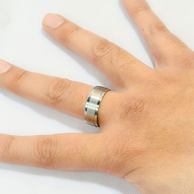 Anillo tipo alianza de matrimonio o pareja en acero inoxidable biselado y ancho de 8mm. Se incluye grabado de nombres y fecha importante gratis. Posa sobre mano hombre.