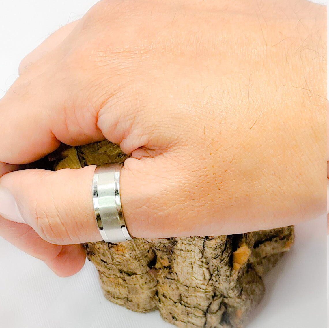 Anillo tipo alianza de matrimonio o pareja en acero inoxidable biselado y ancho de 8mm. Se incluye grabado de nombres y fecha importante gratis. Posa sobre mano hombre.