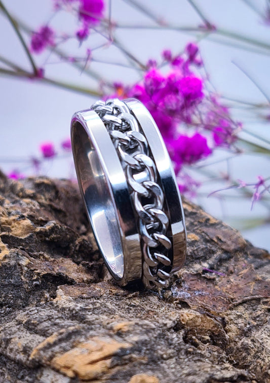 Anillo tipo alianza de matrimonio o pareja en acero inoxidable con cadena y ancho de 8mm. Se incluye grabado de nombres y fecha importante gratis. Posa sobre tronco.