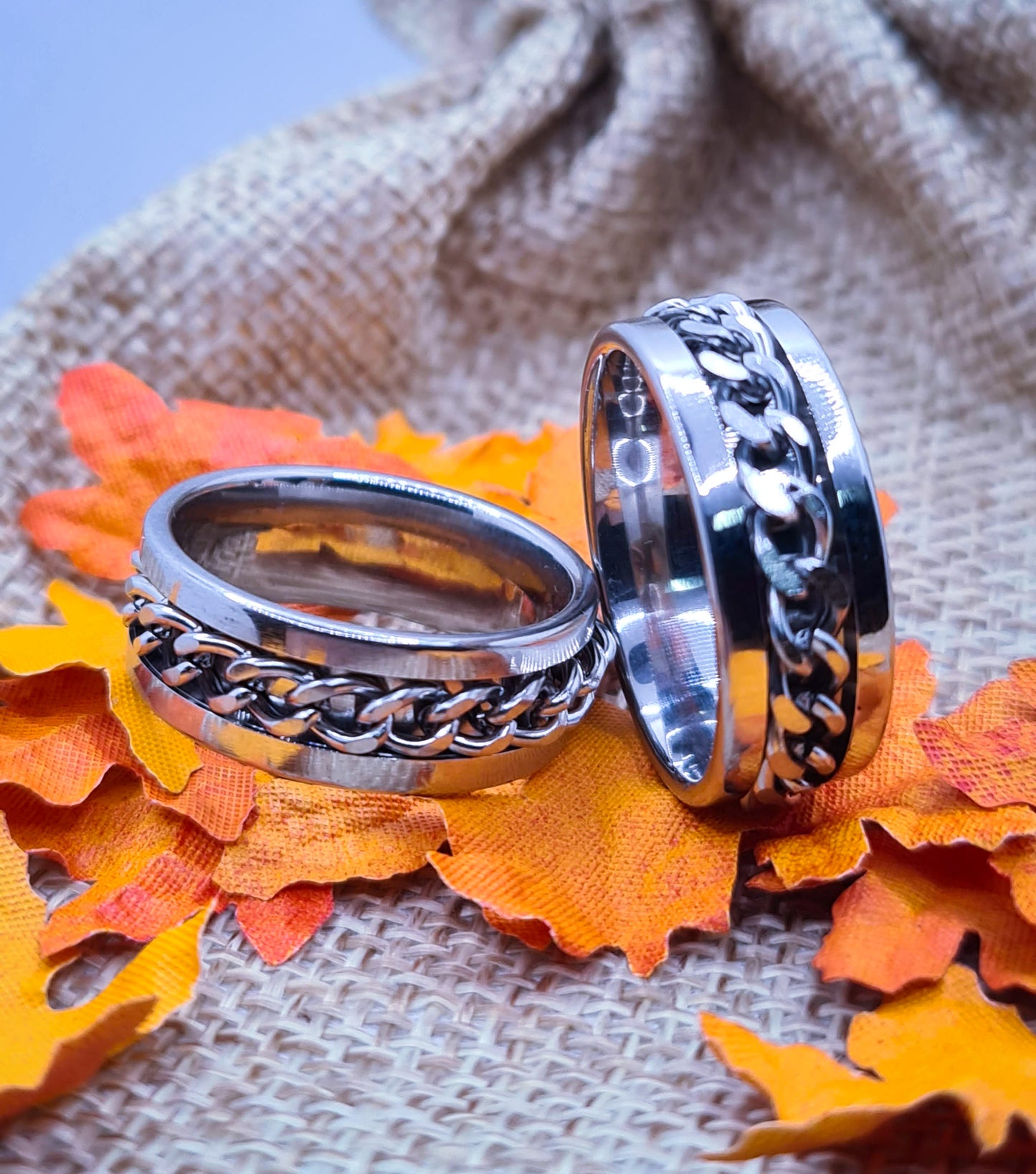 Dos Anillos tipo alianza de matrimonio o pareja en acero inoxidable con cadena y ancho de 8mm. Se incluye grabado de nombres y fecha importante gratis. Posan sobre saco.