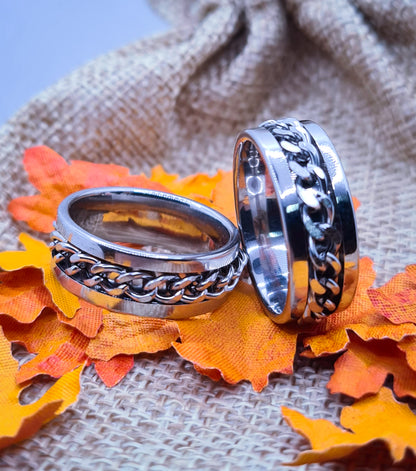 Dos Anillos tipo alianza de matrimonio o pareja en acero inoxidable con cadena y ancho de 8mm. Se incluye grabado de nombres y fecha importante gratis. Posan sobre saco.