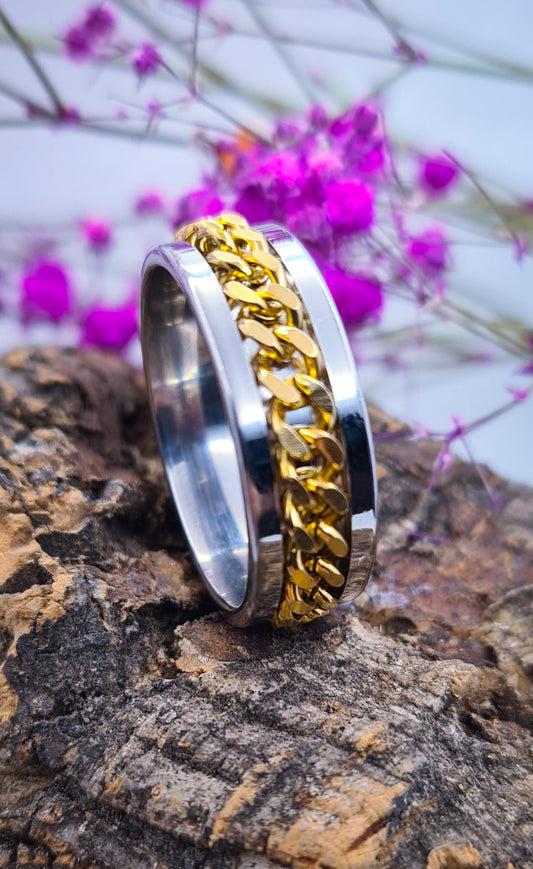 Anillo tipo alianza de matrimonio o pareja en acero inoxidable con cadena dorada y ancho de 8mm. Se incluye grabado de nombres y fecha importante gratis. Posa sobre tronco.