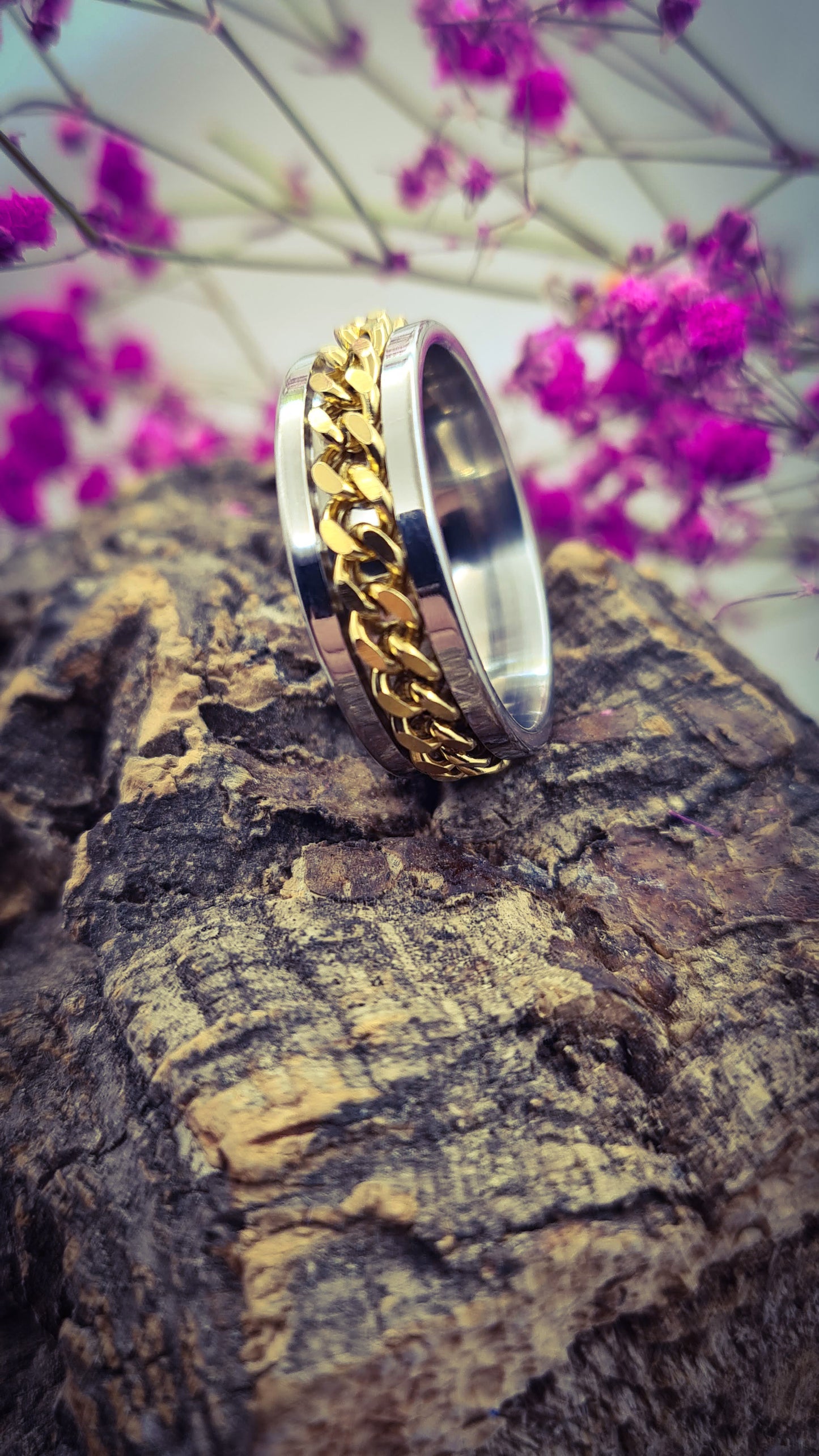 Anillo tipo alianza de matrimonio o pareja en acero inoxidable con cadena dorada y ancho de 8mm. Se incluye grabado de nombres y fecha importante gratis. Posa sobre tronco.